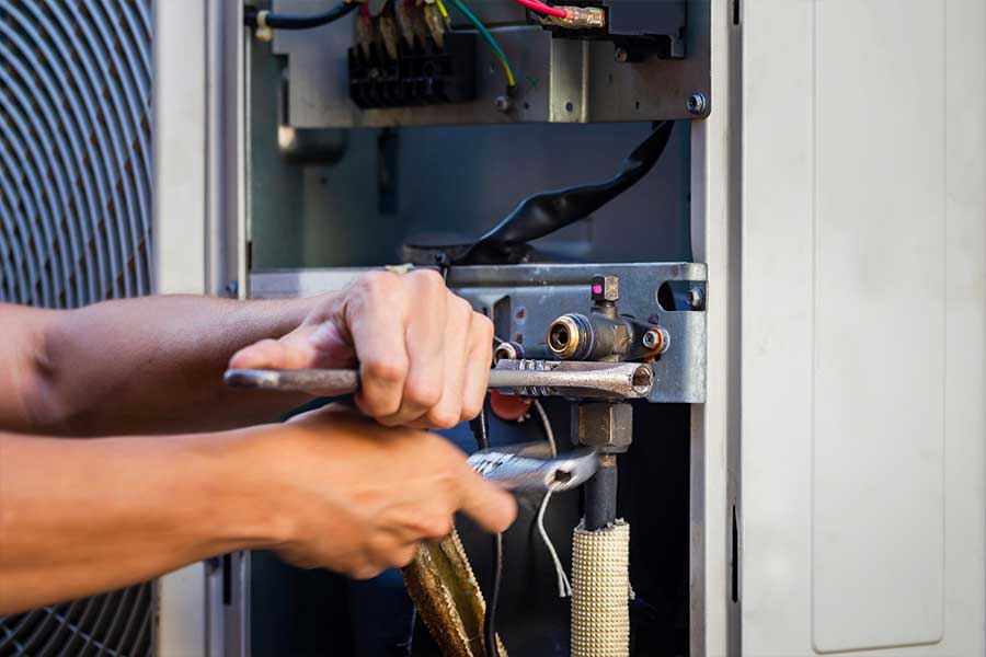 Technician performing HVAC repair on an outdoor unit by adjusting service line connections