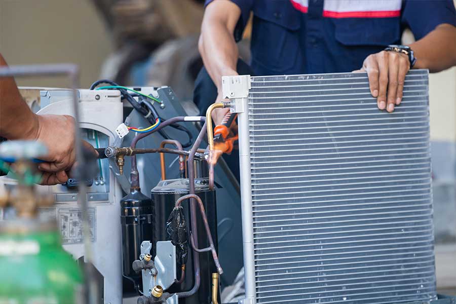 HVAC repair technician working on an outdoor unit with exposed coils and copper lines